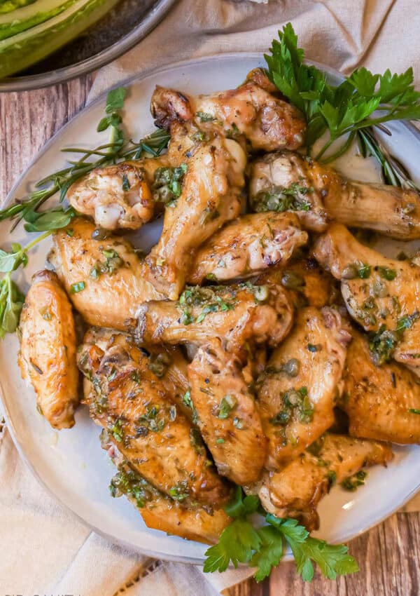 A platter of grilled italian chicken wings garnished with herbs and lemon dressing.