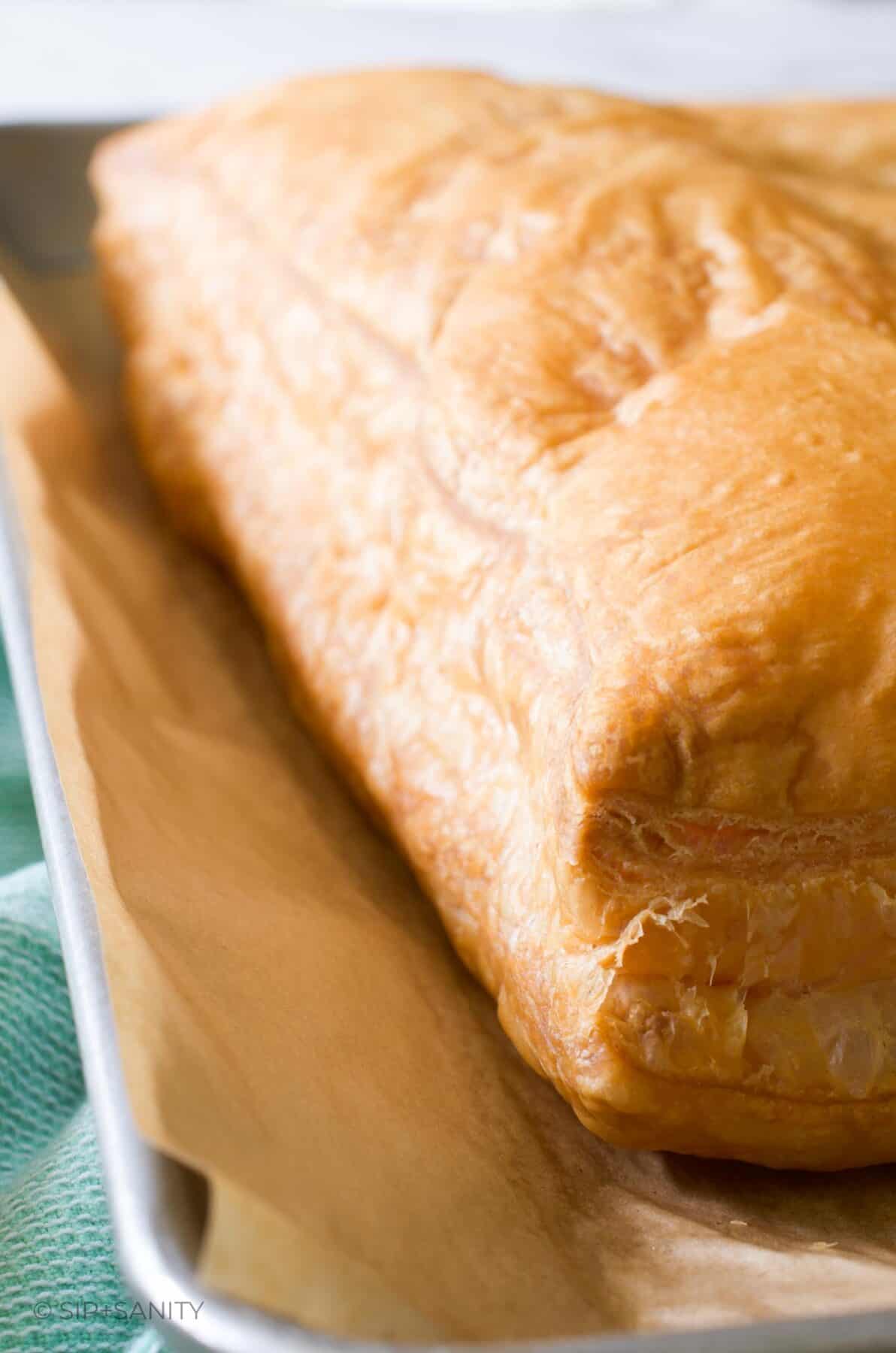 A whole sheet of puff pastry on a sheet pan that has been baked into a giant puff.