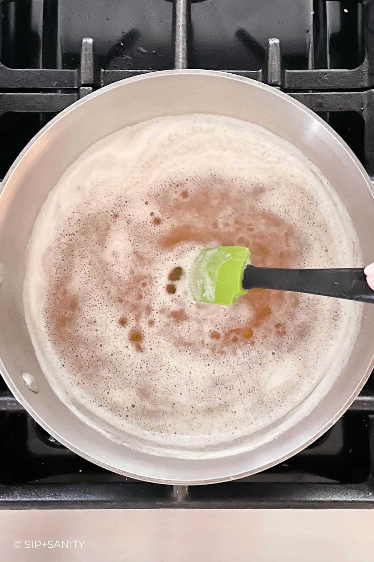Beer simmering in a saucepan on a cooktop.