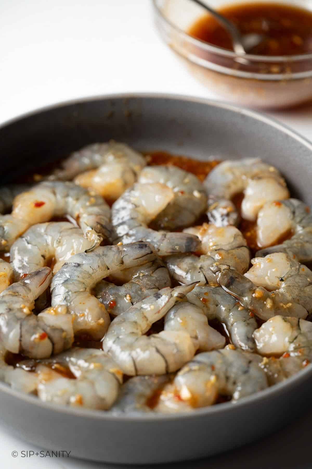 Shrimp marinating in a shallow bowl.