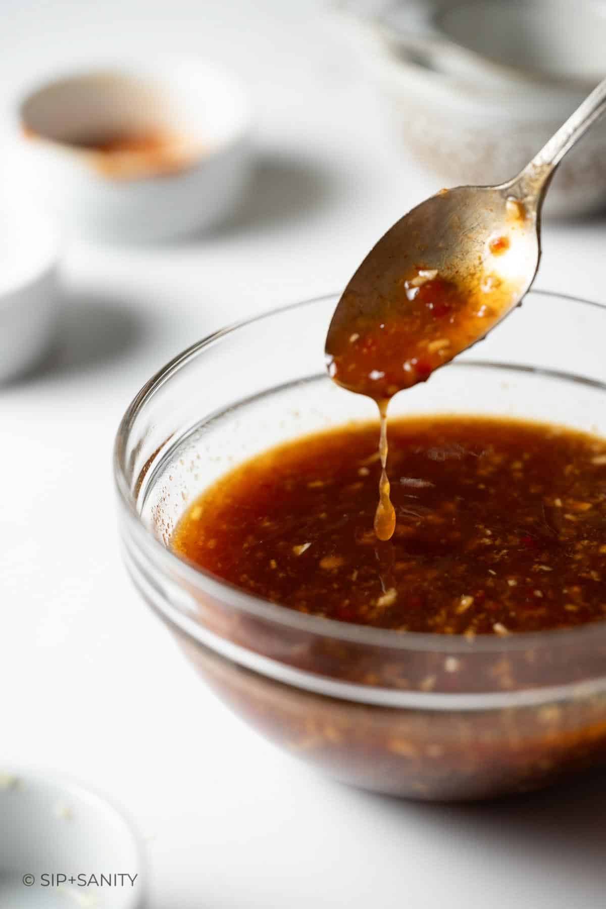 Sweet and spicy shrimp marinade dripping off a spoon into a bowl.