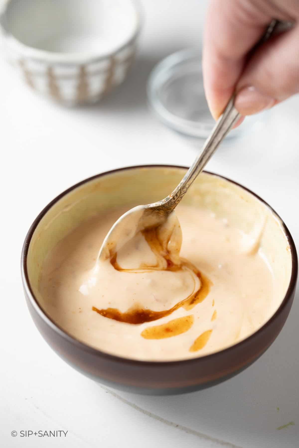 A spoon stirring together a dipping sauce.