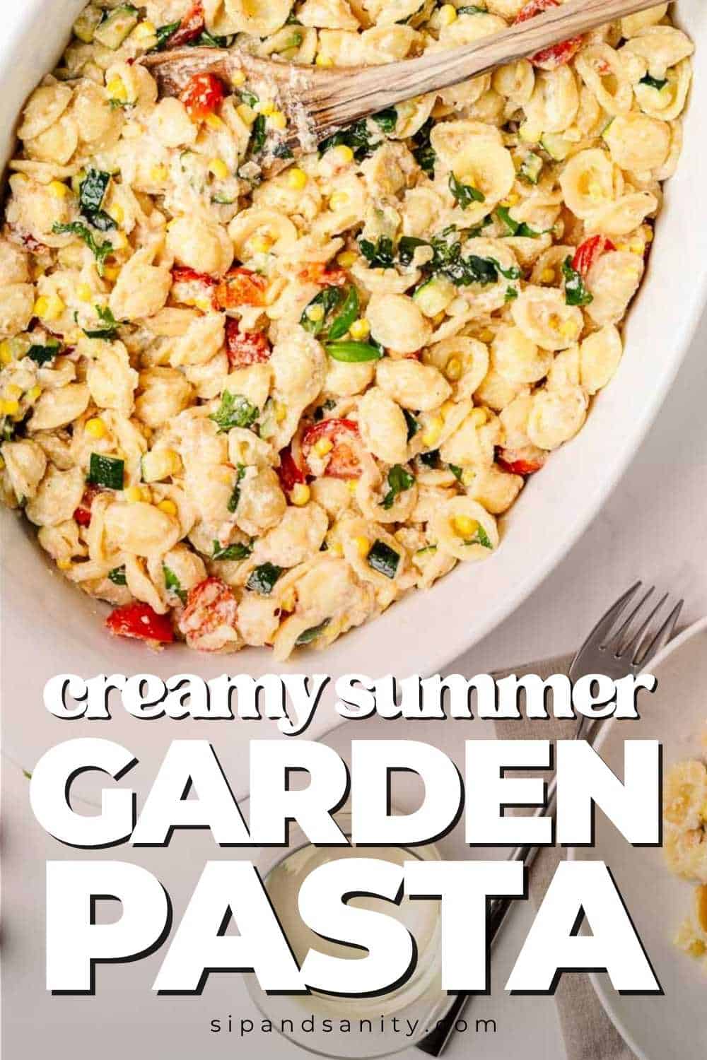 Overhead view of a white dish filled with creamy pasta mixed with colorful summer vegetables and herbs; bold text reads creamy summer garden pasta.