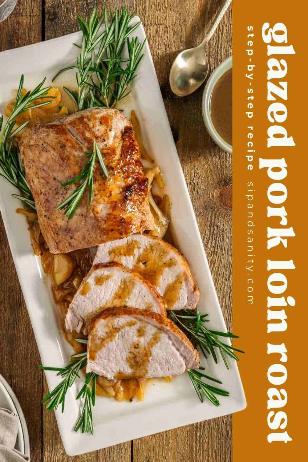 Sliced glazed pork loin roast on white platter with rosemary, onions, spoon, small dish; label reads Glazed pork loin roast.
