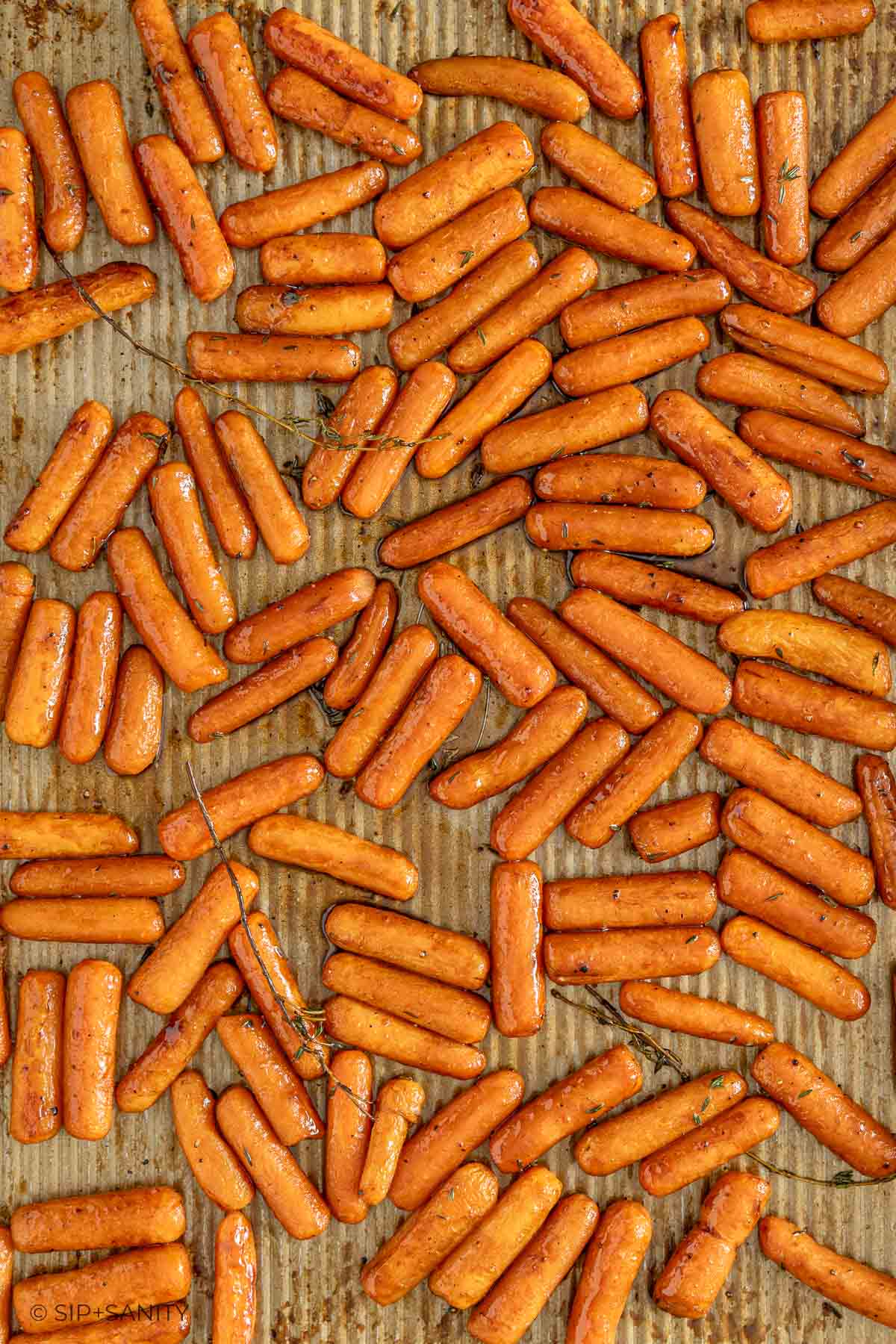 Glazed baby carrots roasted to a shiny golden-brown on a baking sheet.