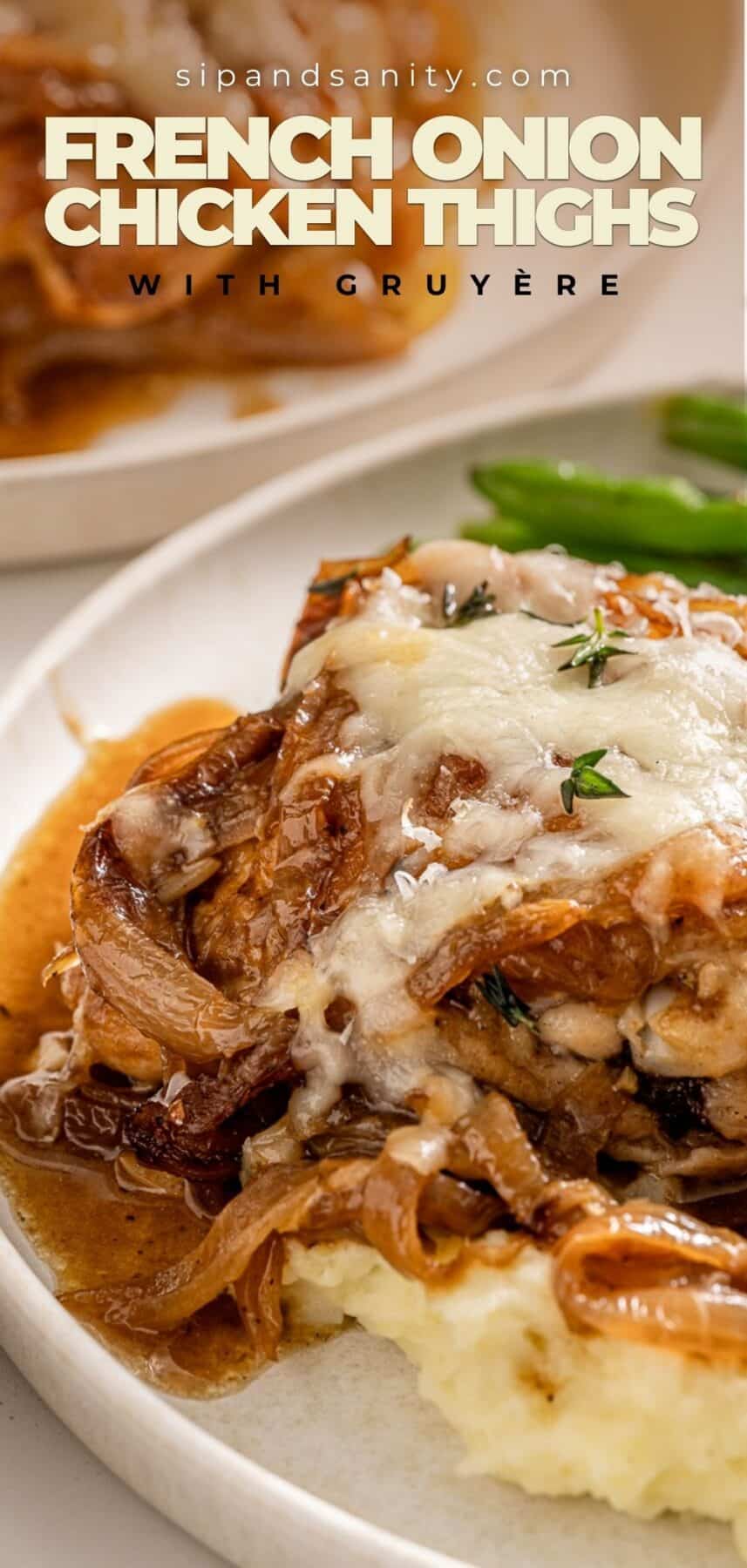 French onion chicken thighs with Gruyère and caramelized onions over mashed potatoes and green beans on a white plate.