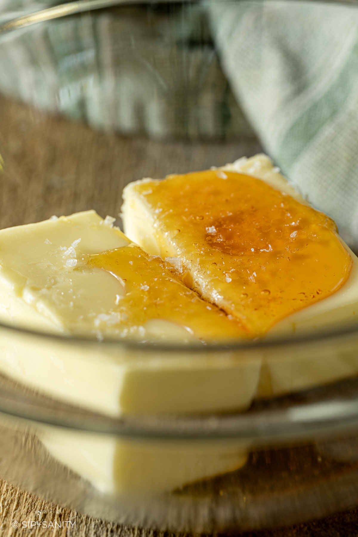 Butter slices in a glass bowl topped with honey and flaky salt.