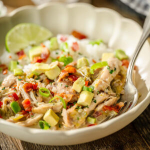 Shredded chicken, avocado, green onions, and red peppers over rice with a lime wedge; spoon in the bowl.