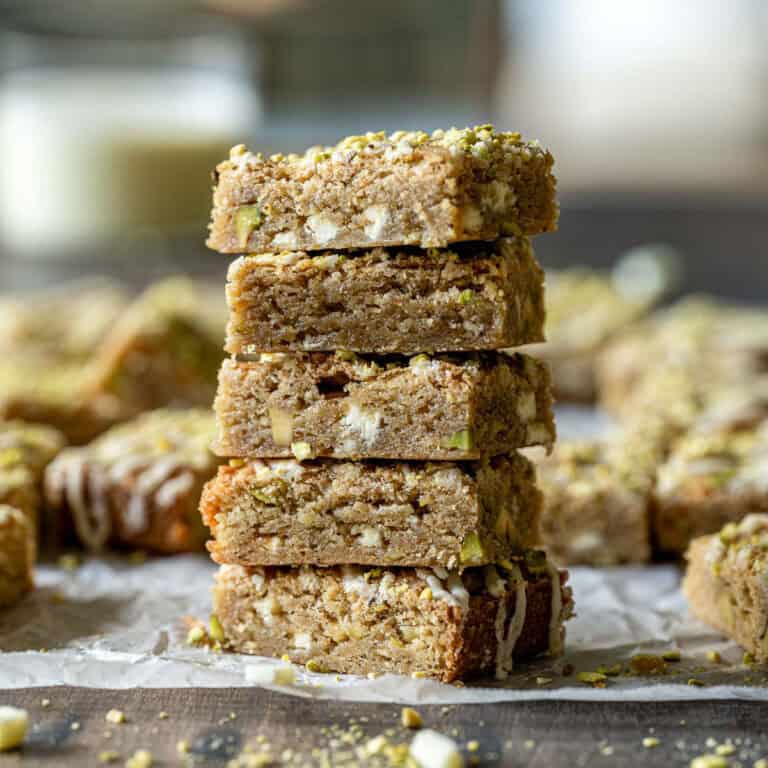 A vertical stack of five eggnog blondies on parchment paper.