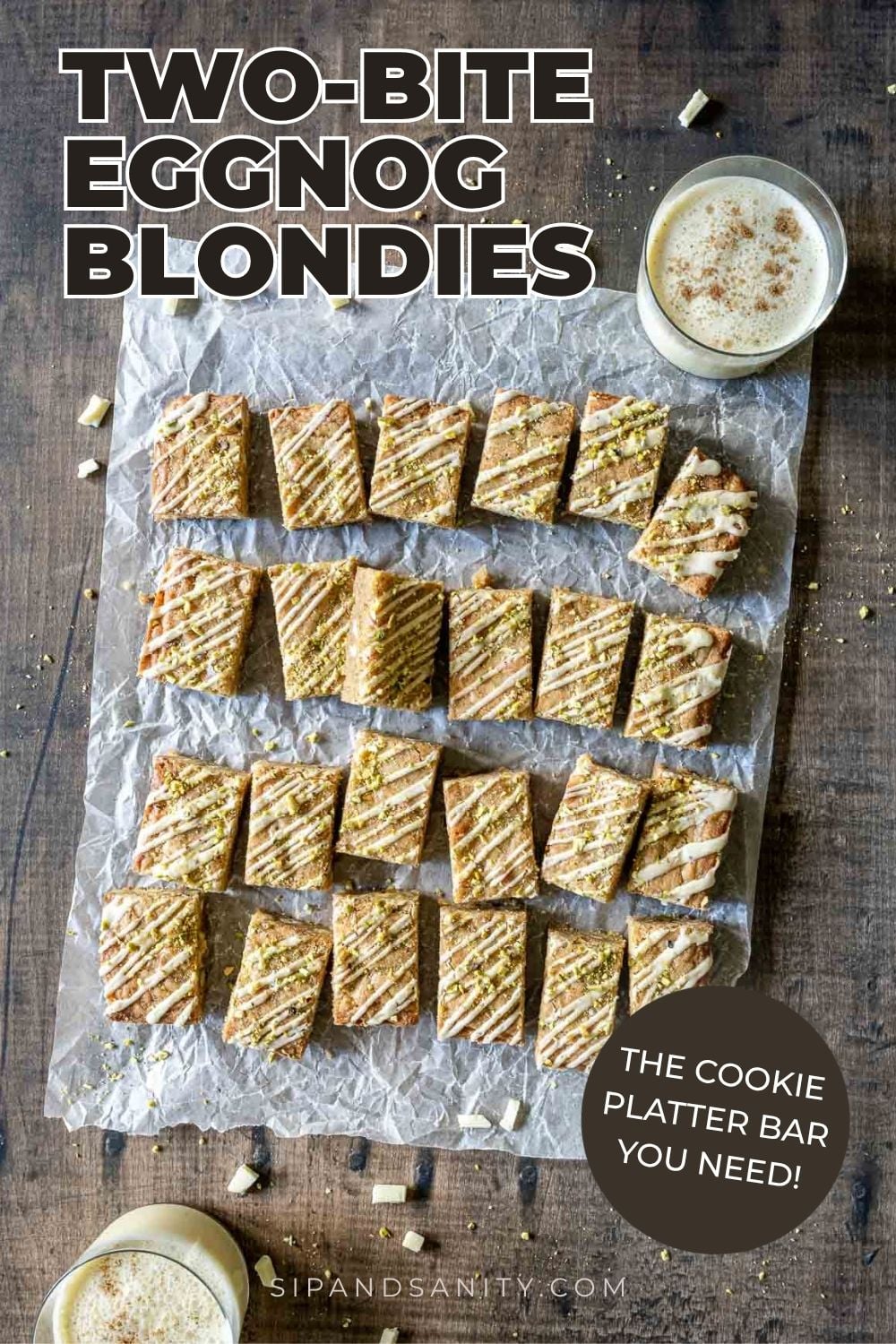Iced eggnog blondies topped with crushed pistachios on parchment paper, served with glasses of eggnog.