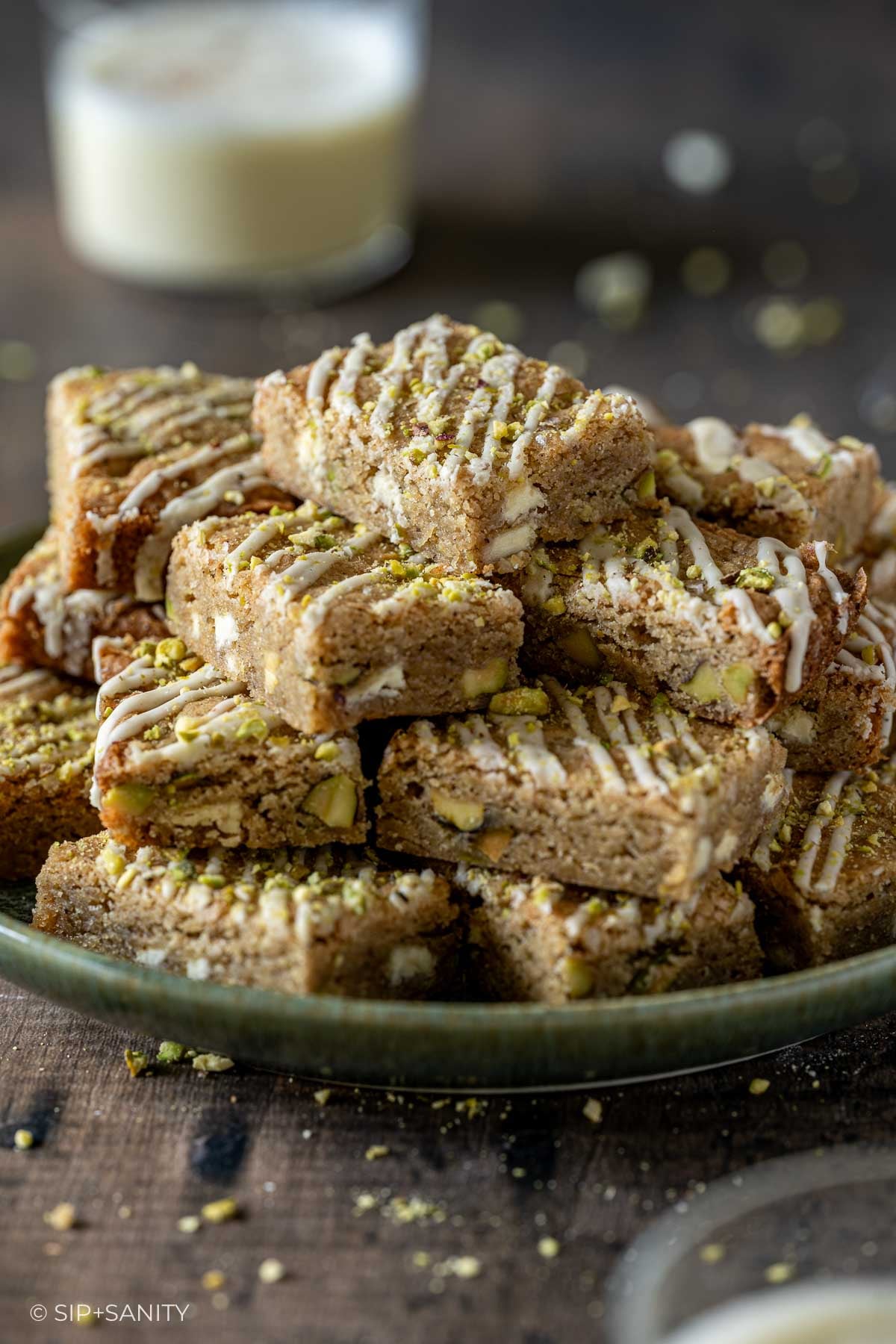 A stack of square eggnog blondies drizzled with white icing on a plate.